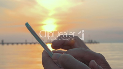 Typing in Smartphone at Sunset