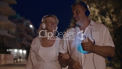 Senior couple listening to music during night walk
