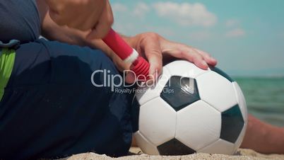 Man pumping a football on the shore