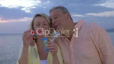 Mature couple blowing bubbles on the coast