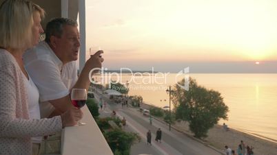 Couple drinking wine and looking at resort from balcony