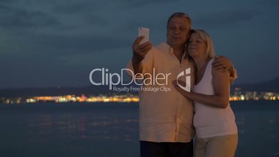 Senior couple on vacation taking cell selfie at night