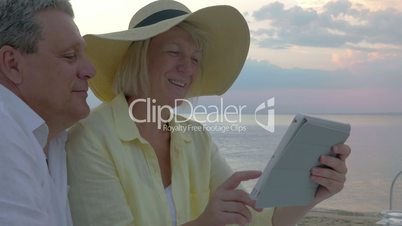 Senior couple using touch pad at the seaside