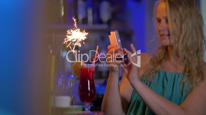 Woman making selfie with cocktail and sparkler