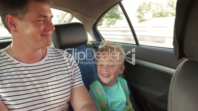 Cheerful father and son traveling by car