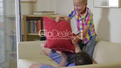 Son and dad fighting with pillows at home