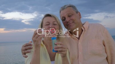 Happy senior couple blowing bubbles on the beach