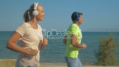 Couple in headphones jogging along the sea front