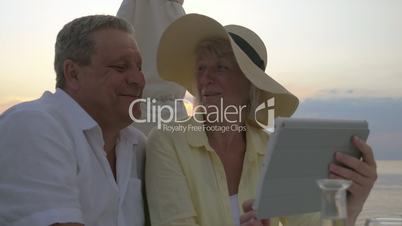 Mature Couple Watching Photos in Tablet and Laughing
