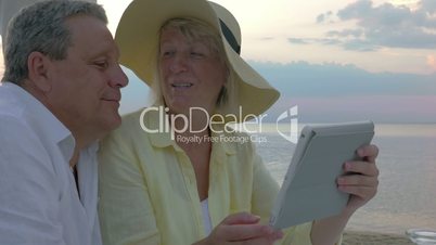 Senior couple using touch pad at the seaside