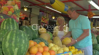 Man and woman choosing melon in market