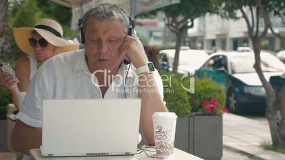 Man wearing headset video chatting in outdoor cafe