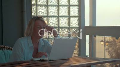 Mature Woman with Laptop on the Balcony
