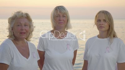 Three women with pink breast cancer awareness ribbons