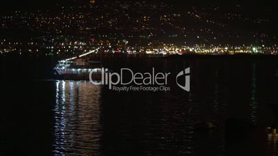 Touristic ship sailing along night city