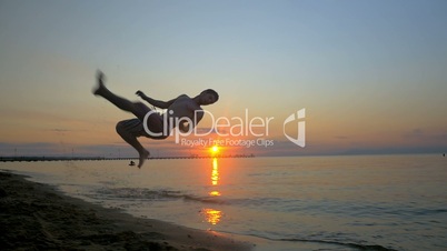 Athlete doing acrobatic tricks on the beach at sunset