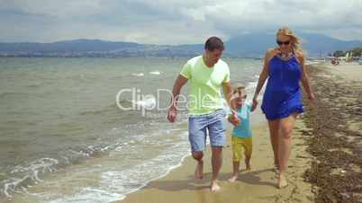 Barefoot family of three running along the sea