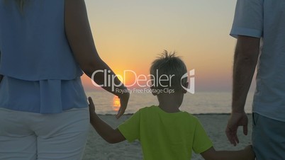 Family with child looking at sunset over sea
