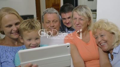 Family with child watching interesting video on pad