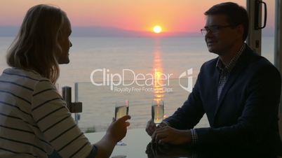 Couple toasting with wine and enjoying sunset over sea