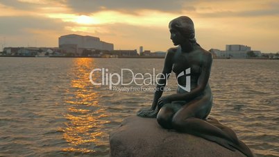 Mermaid statue on the stone in sea at sunset