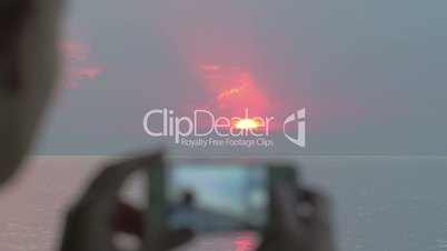 Woman taking sunset pictures with iPhone