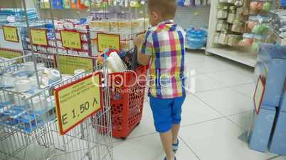 Little boy rolling shopping cart in supermarket