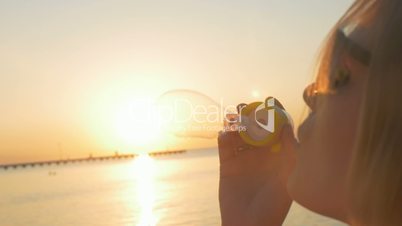 Woman blowing bubbles on the beach at sunset