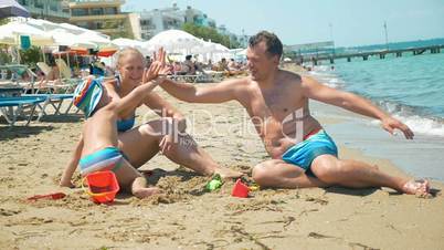 Family of three giving hi-fives on the beach