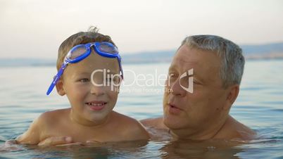 Child and grandfather bathing in the sea