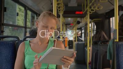 Happy pretty blonde with tablet PC riding in the bus