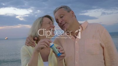 Senior couple blowing bubbles at the seaside