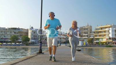 Senior couple jogging with music on the pier