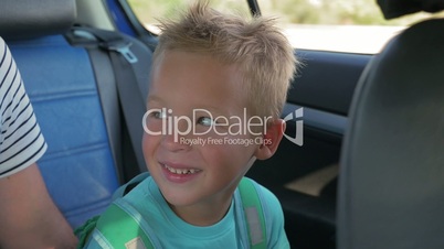Happy little child with backpack traveling by car