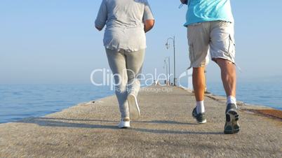 Senior couple jogging on the pier