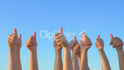 Hands up with thumbs-up against blue sky