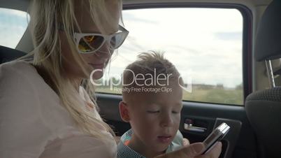 Child playing with mothers smartphone in the car