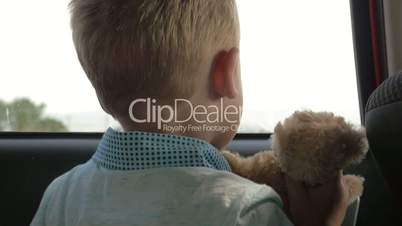 Child traveling in car with favourite teddy bear