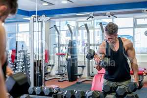 Man exercising with dumbbells in front of mirror
