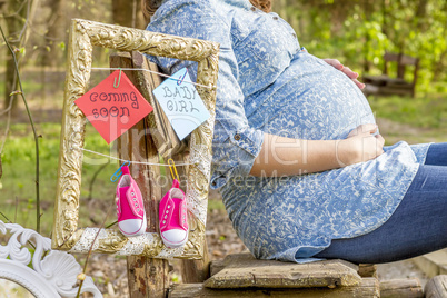 Pregnant woman outdoor in the park on bench