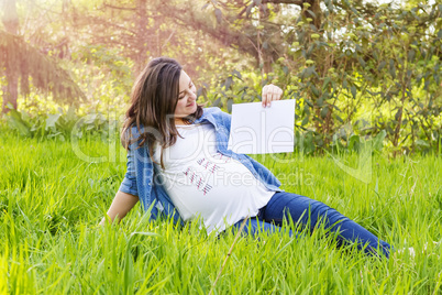 Pregnant woman outdoor with a paper in hand