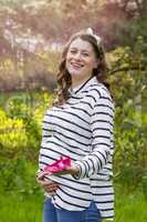 pregnant woman holding baby shoes in her hands in a park
