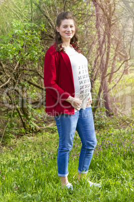 Pregnant woman in red jacket with calendar on her T-shirt