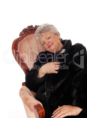 Senior woman sitting in pink armchair.