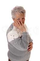 Older senior woman holding hand on face.