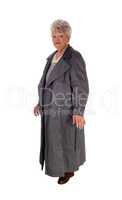 Senior woman standing in a long coat.