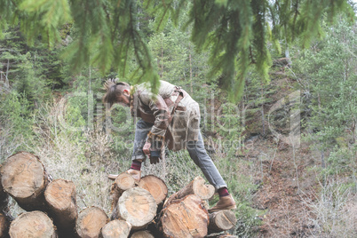 Young men on logs in the forest. Pine trees