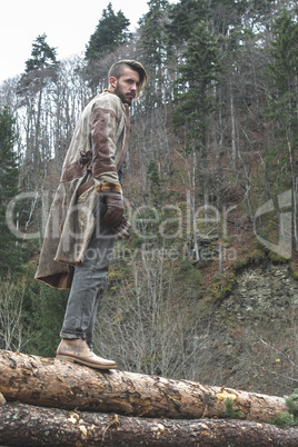 Young men on logs in the forest. Pine trees