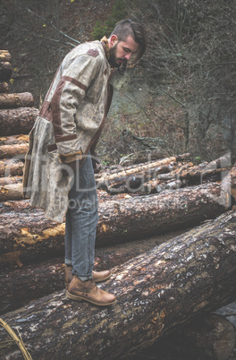 Young men on logs in the forest. Pine trees