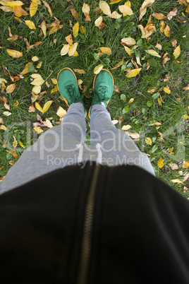 Feets on a green meadow with autumn leaves